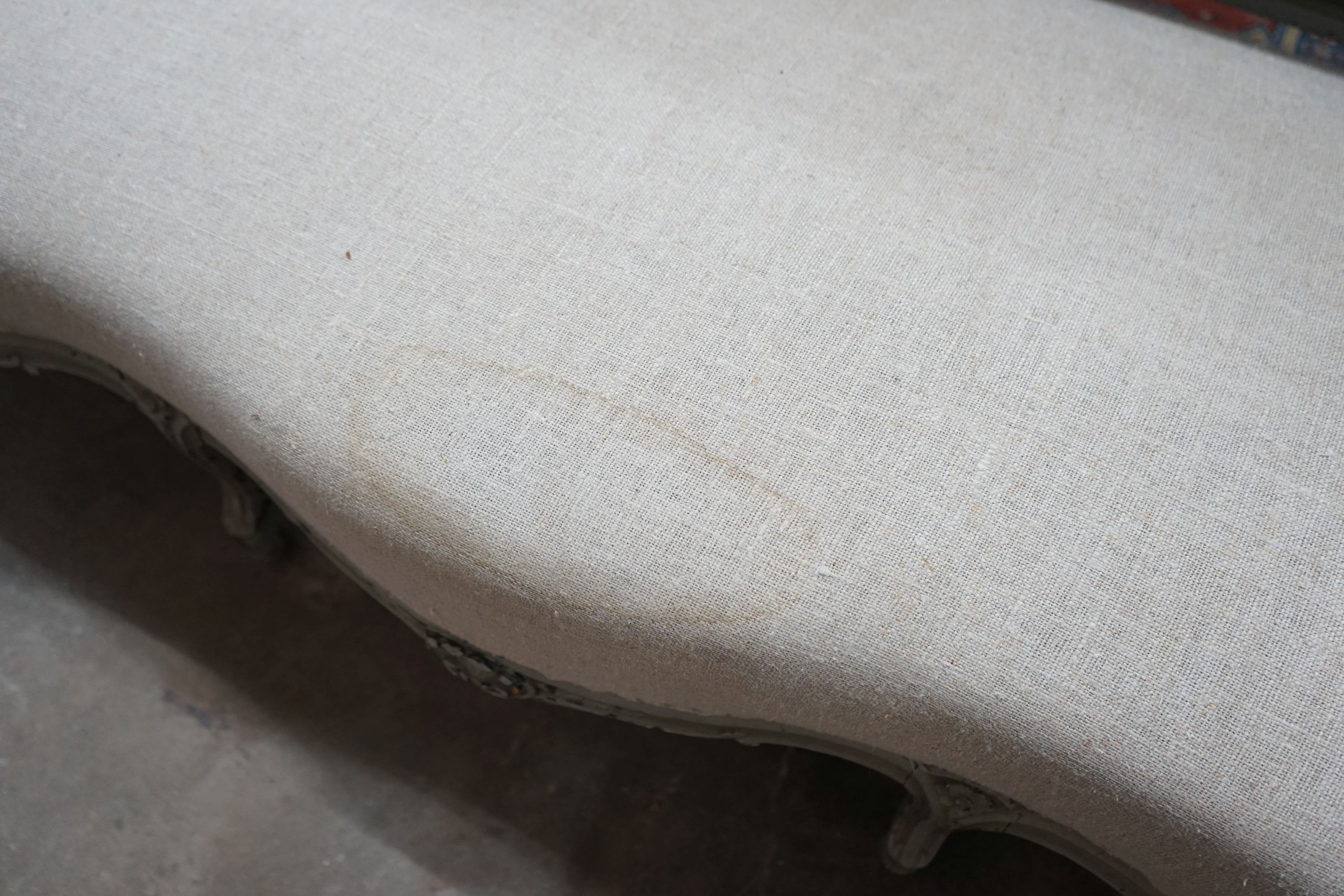 A 19th century French carved wood settee upholstered in a natural linen type fabric, re-painted in grey, length 180cm, depth 60cm, height 102cm